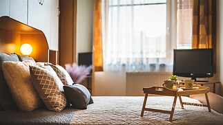 Útulná ložnice s moderním stylem, velká okna a parketová podlaha, pohodlná postel a vestavěné skříně vytváří příjemnou atmosféru.