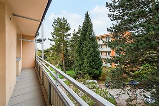 Balkon s dlažbou, s výhledem na zeleň, udržovaný bytový dům v klidné lokalitě, kovové zábradlí poskytuje bezpečnost a styl.