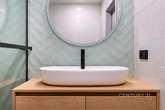 Moderní koupelna s elegantním umyvadlem, dřevěným podstavcem a stylovými obklady zelené barvy, světlý a čistý designový interiér.
