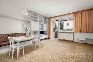 Světlý obývací pokoj s velkými okny, parketovou podlahou a vestavěnými skříněmi nabízí moderní a útulný prostor k bydlení.