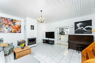 Světlý obývací pokoj s bílou dlažbou, krbová kamna, stylový lustr a moderní dekorace, ideální pro rodinný relax.