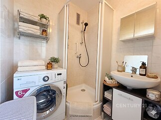 Malá koupelna s moderní sprchou, světlými dlažbami a vestavěným zrcadlovým skříňovým úložným prostorem.