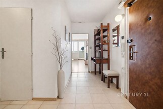 Vstupní chodba s dlažbou, dřevěným nábytkem a moderním osvětlením působí světlým a prostorným dojmem, ideální pro elegantní přechod mezi místnostmi.