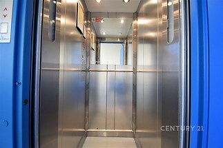 Prázdný výtah s nerezovým interiérem a světlými stěnami, moderní styl, dobrá údržba, jasné osvětlení, vhodný pro obytné či kancelářské budovy.