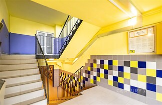 Světlé schodiště s moderní dlažbou a barevnými obklady, dobře udržovaný stav, vhodné pro bytový dům nebo komerční prostory.