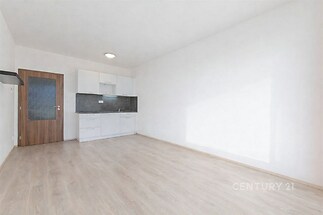 Světlý obývací pokoj s moderní kuchyní, parketová podlaha, vestavěné skříně, minimalistický styl.