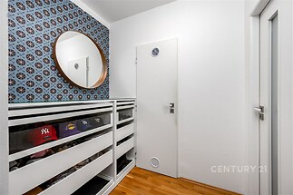 Vstupní předsíň s parketovou podlahou, vestavěnými skříněmi a stylovou tapetou nabízí moderní a praktický prostor.