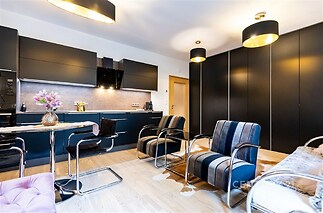 Moderní kuchyň s parketovou podlahou, vestavěné skříně a elegantní osvětlení, stylový a světlý interiér