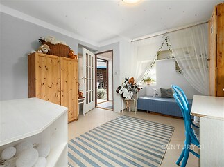 Světlý dětský pokoj s dlažbou, vestavěnými skříněmi a moderním nábytkem. Velká okna poskytují dostatek přirozeného světla.