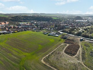 Zemědělský pozemek s výhledem na obec, rovinatá lokalita, strategická poloha poblíž zástavby. Potenciál pro různé využití.
