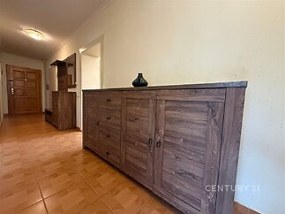 Prostorná předsíň s dřevěným nábytkem, dlažbou na podlaze, moderní osvětlení, nabízí elegantní úložné prostory.