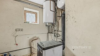 Prádelna s elektrickým bojlerem a připojením pro pračku, dlažba na podlaze, světlé stěny, ideální pro úklidové a technické zázemí domácnosti.