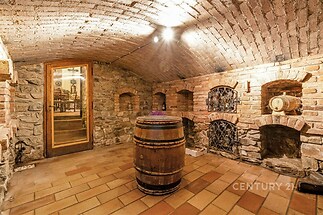 Kamenný vinný sklep s klenutým stropem, cihlové zdi a dlažba, dřevěný sud, rustikální design.