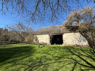 Prázdná stodola s kamennou fasádou na rozlehlém zeleném pozemku, ideální pro rekonstrukci a rozšíření obytných prostor, v klidné lokalitě.