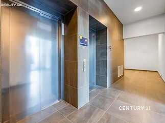 Moderní vstupní hala s dlažbou a nerezovým výtahem, čistý design a světlé osvětlení pro pohodlný vstup do budovy.