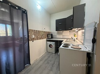 Kompaktní kuchyň s moderní dlažbou, tmavými skříňkami a pračkou, ideální pro efektivní využití prostoru v rekonstruovaném interiéru.