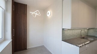 Moderní kuchyň s vestavěnými skříněmi, dlažbou a bílými skříňkami, vybavená elegantním osvětlením a nerezovým dřezem.