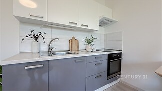 Moderní kuchyň s parketovou podlahou, vestavěné skříně a světlé laminátové pracovní desky, moderní spotřebiče a elegantní design