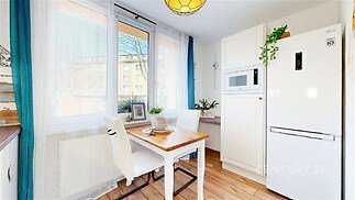 Světlá kuchyň s parketovou podlahou, velkými okny a vestavěnými spotřebiči. Moderní a útulný design zajišťuje příjemnou atmosféru.