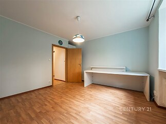 Světlý pokoj s parketovou podlahou, dřevěnými dveřmi a velkými okny, moderní styl nabízí prostor pro kreativní úpravy a pohodlné bydlení.