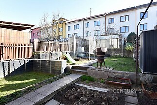 Malá zahrada s trávníkem a zeleninovými záhony, obklopená plotem. Obsahuje skleník, zahradní nábytek a starý kovový gril. Světlé venkovní prostory vhodné k renovaci.