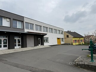 Průmyslová budova s moderní fasádou, asfaltovou plochou a velkými okny, ve výborném technickém stavu.