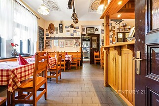 Tradiční jídelna s dřevěným nábytkem, dlažbou a historickými dekoracemi na stěnách, vytváří útulnou atmosféru.