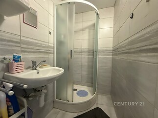 Kompaktní koupelna s moderním sprchovým koutem, keramickými dlaždicemi a praktickým umyvadlem, ideální pro rekonstrukci.