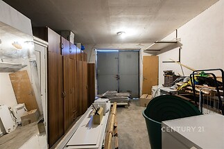 Garážový prostor s betonovou podlahou, vestavěnými skříněmi a úložnými policemi, ideální pro skladování nebo dílnu.