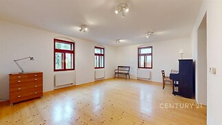 Prostorný obývací pokoj s dřevěnou podlahou, velkými okny a světlým designem, ideální pro moderní bydlení.