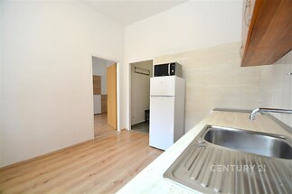 Kuchyň s parketovou podlahou, moderní vestavěná skříň, světlý interiér, velká nerezová dřezová plocha, dřevěné obložení na zdi