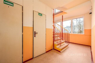 Světlé schodiště s velkými okny a zábradlím, které nabízí výhled na městské panorama. Světlé stěny a nedávno renovovaný interiér.