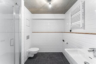 Moderní koupelna s bílými obklady, dlažbou a sprchovým koutem, minimalistický styl s černou dlažbou a stropním svítidlem, světlé provedení