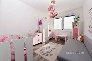 Dětský pokoj s parketovou podlahou, světlý interiér s velkými okny, moderní nábytek v růžových a šedých tónech, ideální pro malé dítě