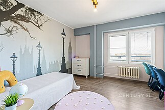 Světlý dětský pokoj s moderní tapetou, laminátová podlaha, velké okno nabízí dostatek světla, což vytváří příjemnou atmosféru.