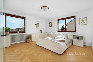 Světlá ložnice, parketová podlaha, velká okna, moderní vybavení, minimalistický styl, příjemné přirozené osvětlení.
