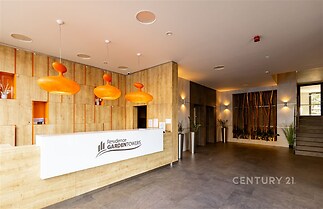 Recepce s moderním designem, dřevěnými obklady a dlažbou. Stylové osvětlení s oranžovými lampami, světlý a prostorný interiér.