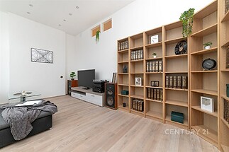 Obývací pokoj s parketovou podlahou, velká knihovna a moderní nábytek, světlý prostor s minimalistickým designem.