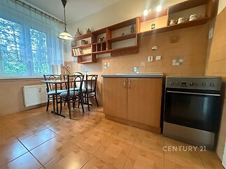 Kuchyň s dlažbou, dřevěnými skříňkami a velkými okny, která poskytují dostatek světla, jídelní kout s moderním osvětlením.