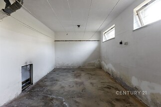 Prázdný sklepní prostor s betonovou podlahou, malými okny a bílými zdmi, ideální pro skladování nebo rekonstrukci na obytný prostor.