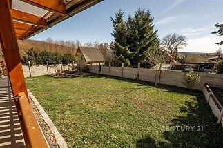 Zahrada s dřevěným altánem, obklopená kamenným plotem a udržovaným trávníkem, nabízí soukromí a klidné prostředí na okraji obce.