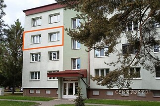Podlaží bytového domu s bílou fasádou a červenou stříškou, plastová okna, udržovaná předzahrádka, klidná lokalita.