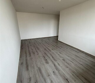 Prázdný obývací pokoj s moderní vinylovou podlahou, bílými stěnami a minimalistickým stylem, ideální pro vlastní úpravy.