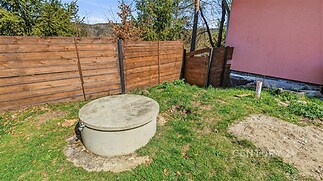 Zahrada s betonovou nádrží, dřevěným plotem a trávníkem, ideální pro rekreační úpravy a soukromí.