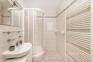 Koupelna s dlažbou a sprchovým koutem, moderní umyvadlo a designový topný žebřík, světlé obklady pro elegantní vzhled.