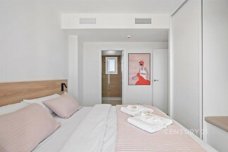 Světlá ložnice s moderním designem, vestavěné skříně, dřevěné detaily a velká okna vytvářející prosvětlený a klidný prostor