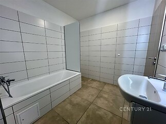 Koupelna s bílými kachličkami, moderními obklady a keramickou dlažbou, prostorná vana, moderní vybavení, světlý interiér