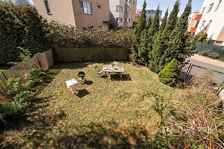 Soukromá zahrada s upraveným trávníkem, obklopená živým plotem a ozdobnými keři. Ideální pro relaxaci a venkovní aktivity.