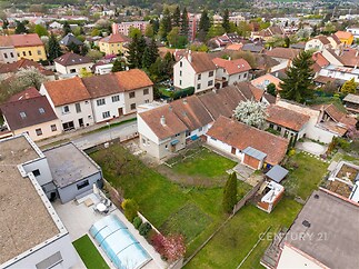 Prostorná zahrada s travnatou plochou a terasou, obklopená rodinnými domy, ve vilové čtvrti.