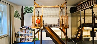 Dětský pokoj s moderní vestavěnou skříní nabízí originální hrací koutek s dřevěnou skluzavkou, ideální pro rodiny s dětmi.